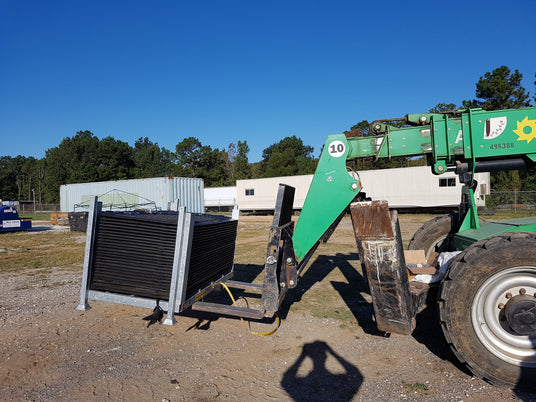 A forklift lifting a crate of ground protection mats